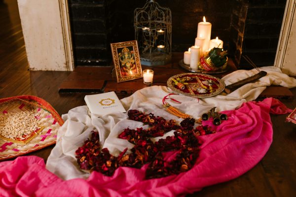 A vibrant setup for a traditional Hindu ceremony featuring candles, flowers, and an image of Ganesha.